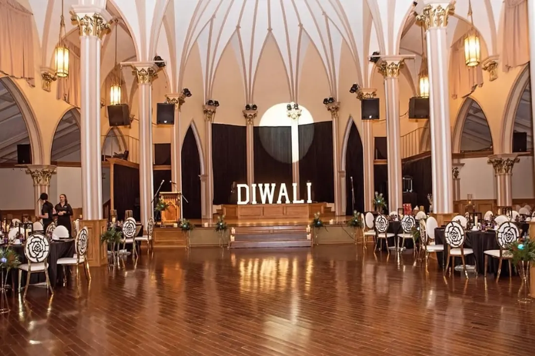 DIWALI spelled in lit marquee letters at the front of a decorated hall